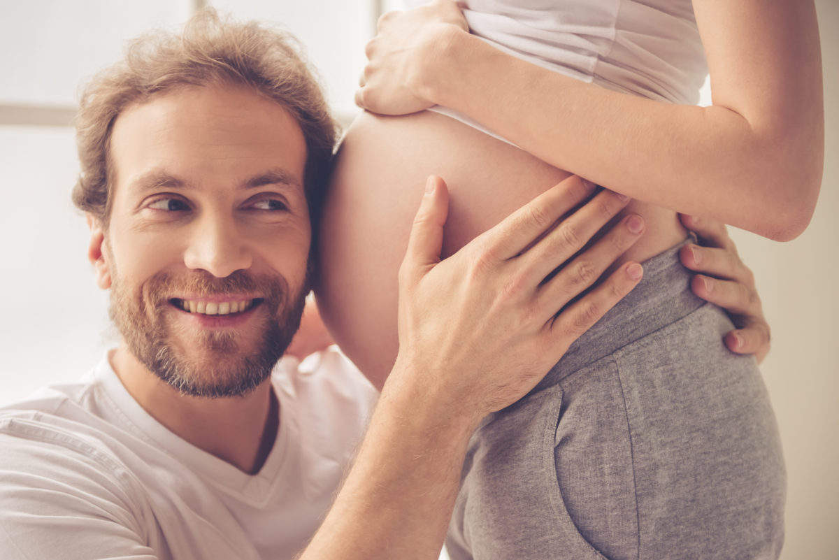 Werdender Vater lauscht am Bauch seiner schwangeren Frau