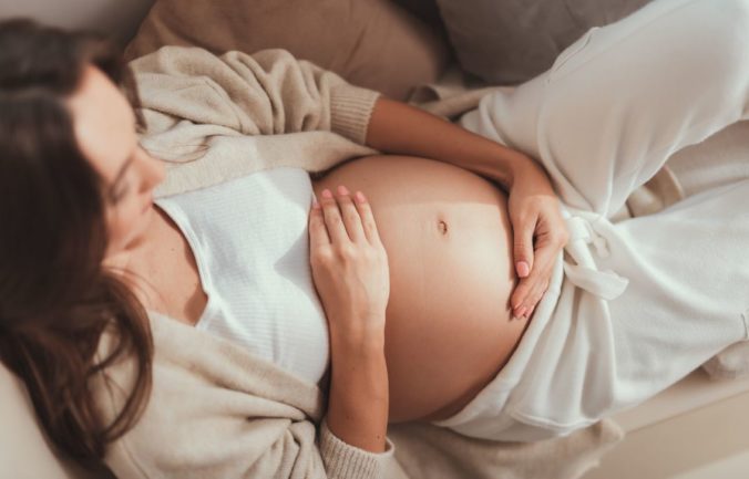 Schwangere Frau guckt auf ihrem Bauch