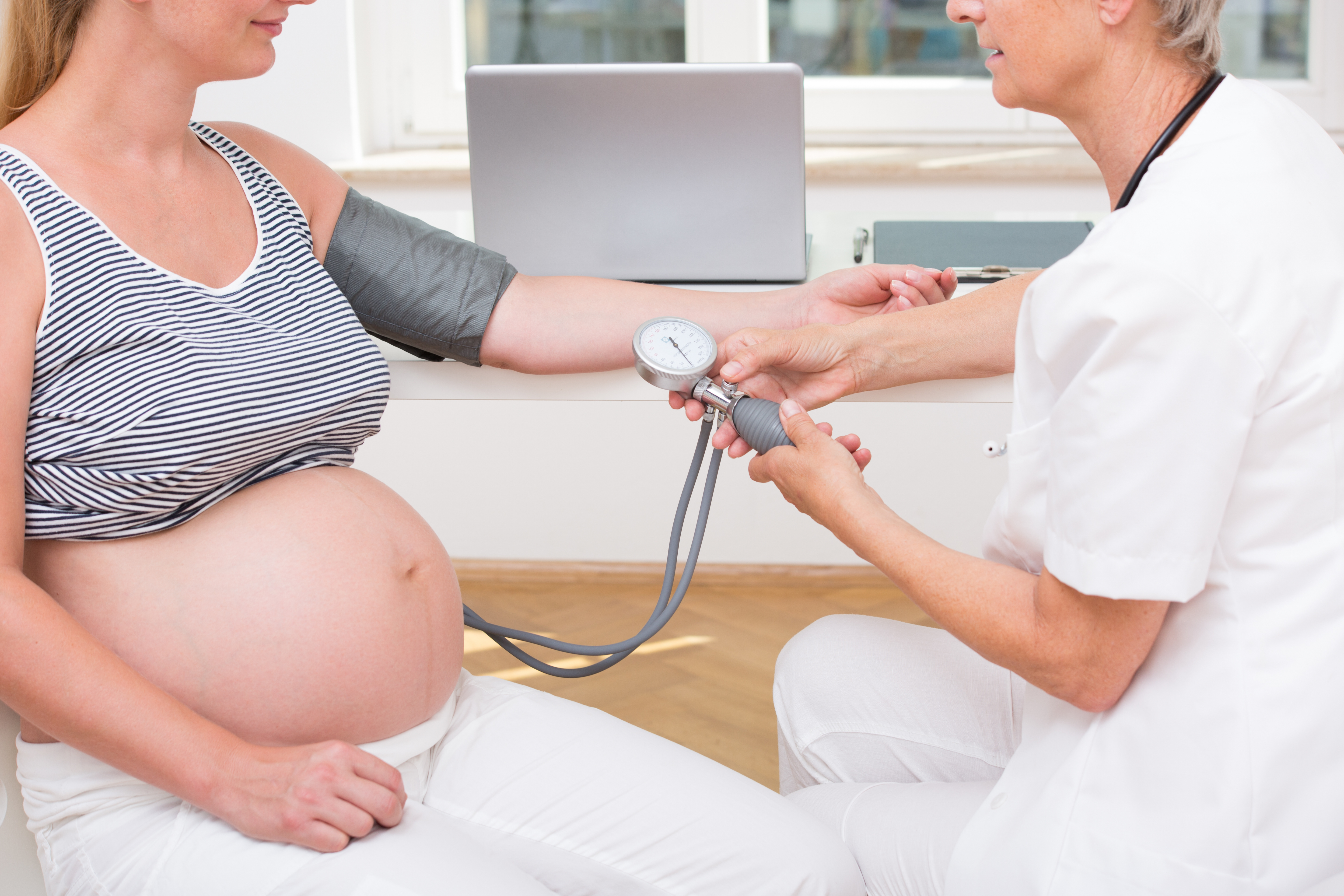 Hebamme misst Blutdruck bei Schwangerer Frau
