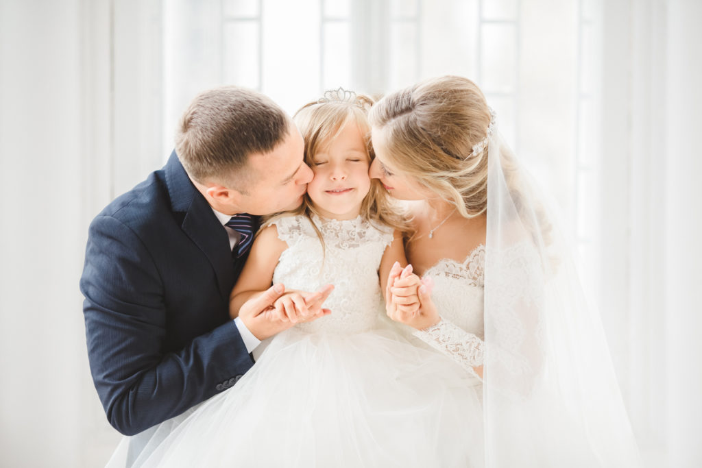 Stiefeltern umarmen Tochter auf Hochzeit