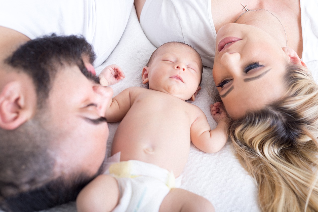 Baby und Eltern liegen auf dem Bett