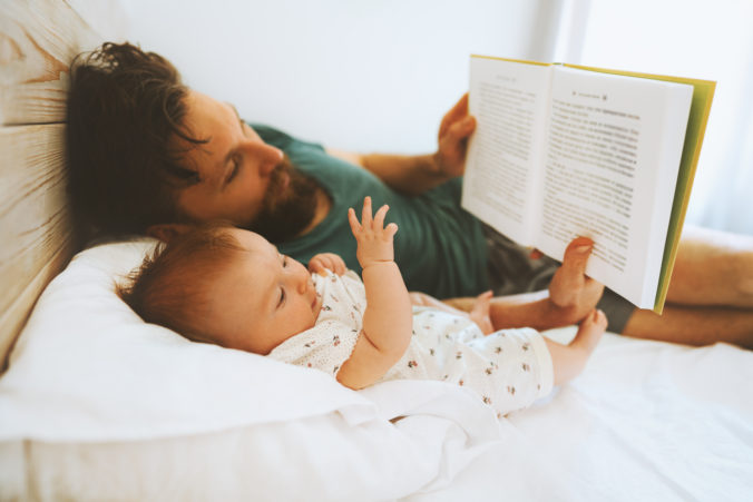 Papa liest seinem Baby im Bett was vor
