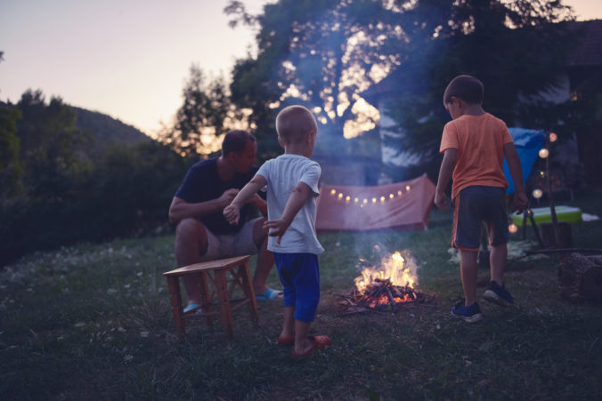 Familie sitzt in Abenddämmerung am Lagerfeuer