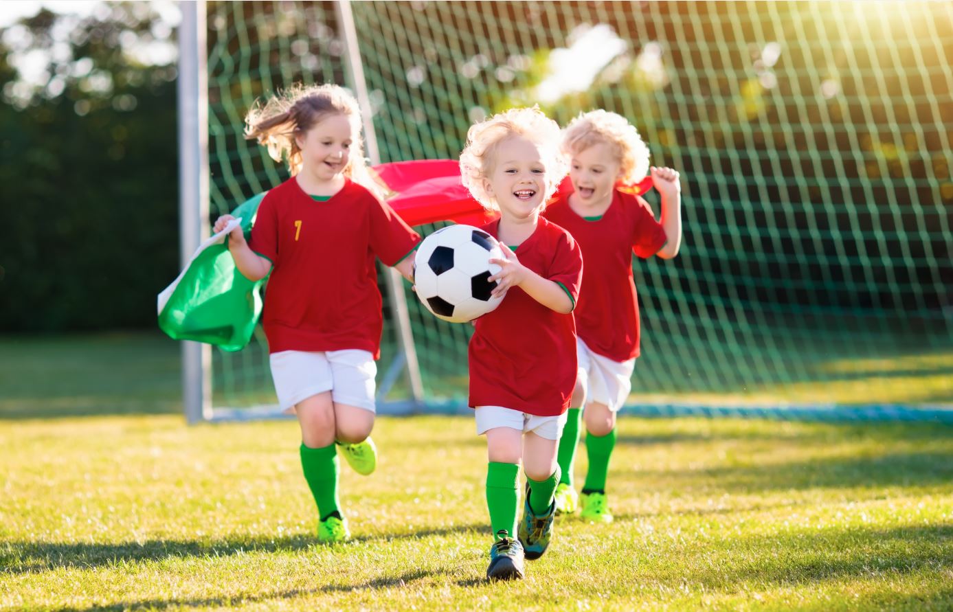 Jungs und Mädchen spielen zusammen Fußball