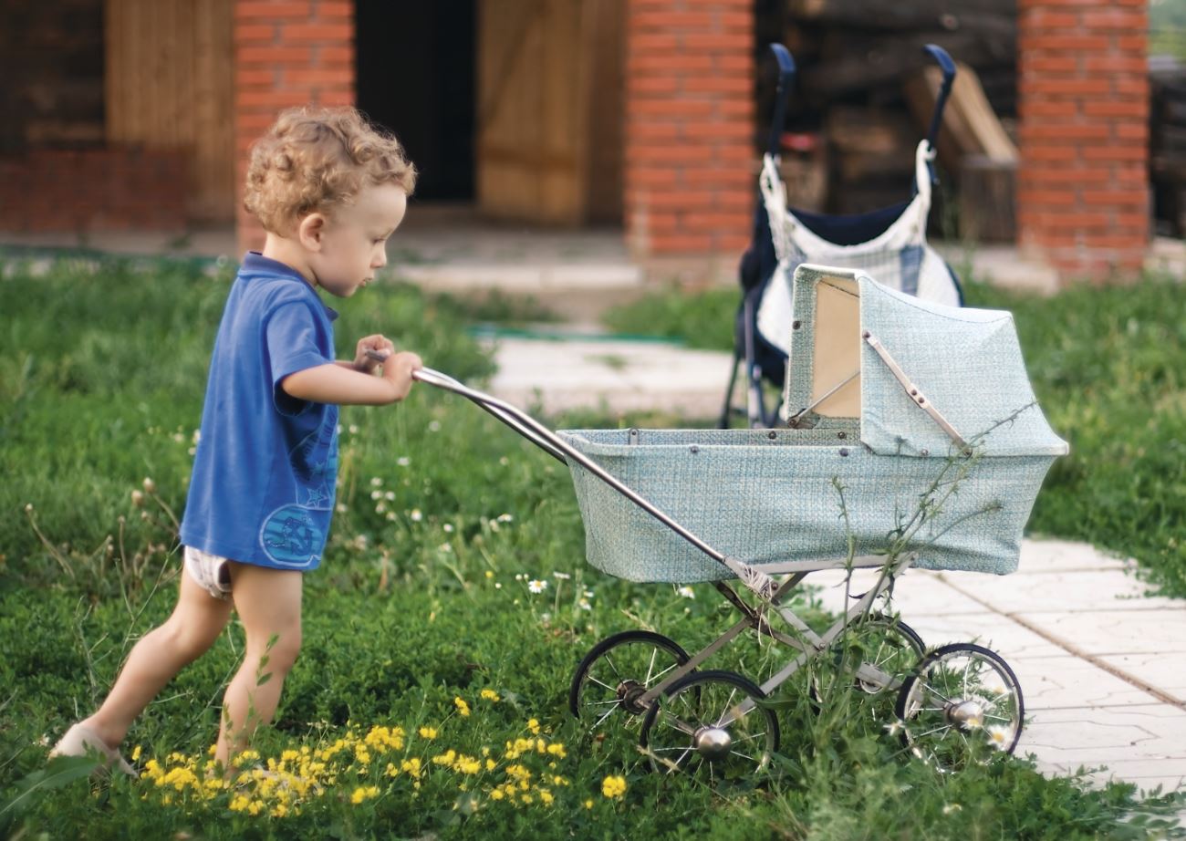 junge schiebt Puppenwagen