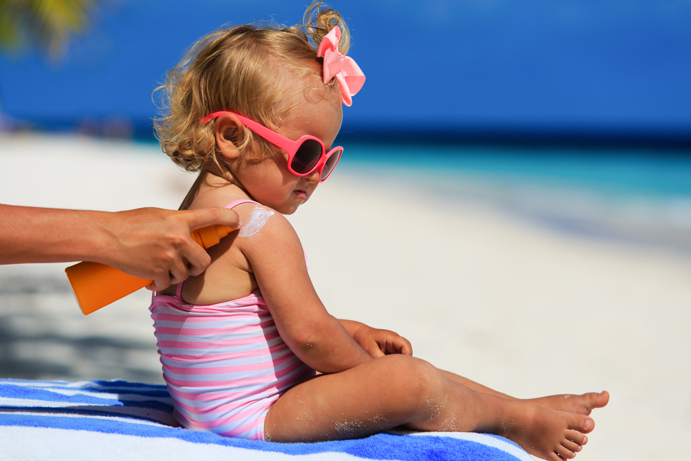 Baby am Strand wird eingecremt