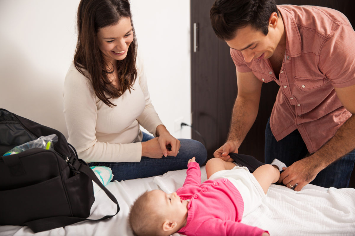 Eltern wickeln gemeinsam Baby