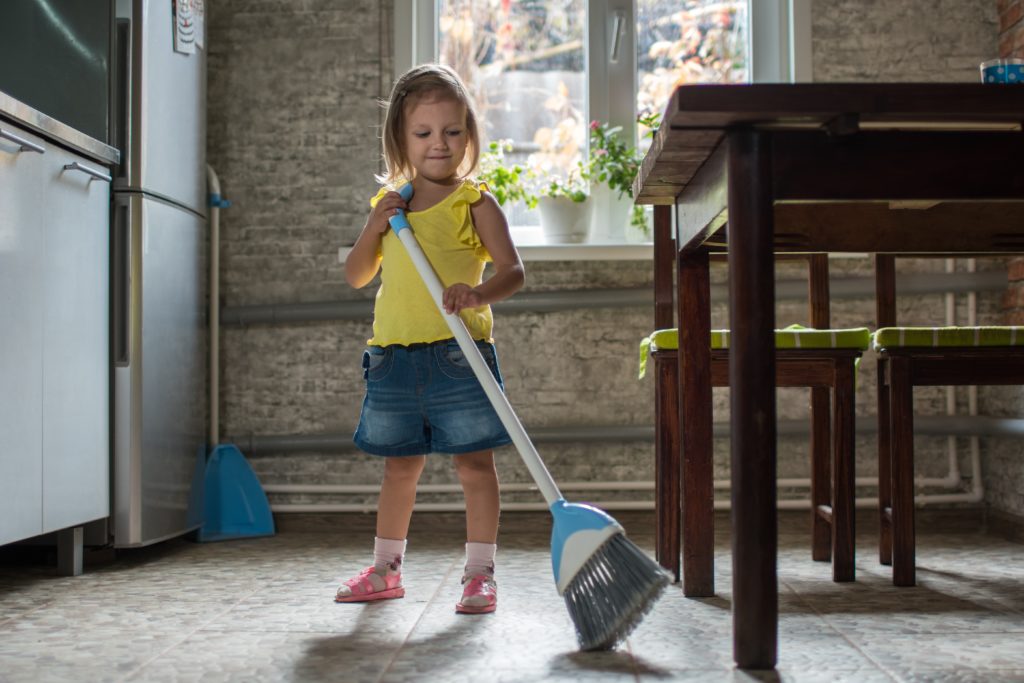 Kind fegt die Wohnung