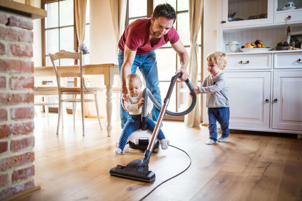 Papa saugt mit seinen Kindern die Wohnung