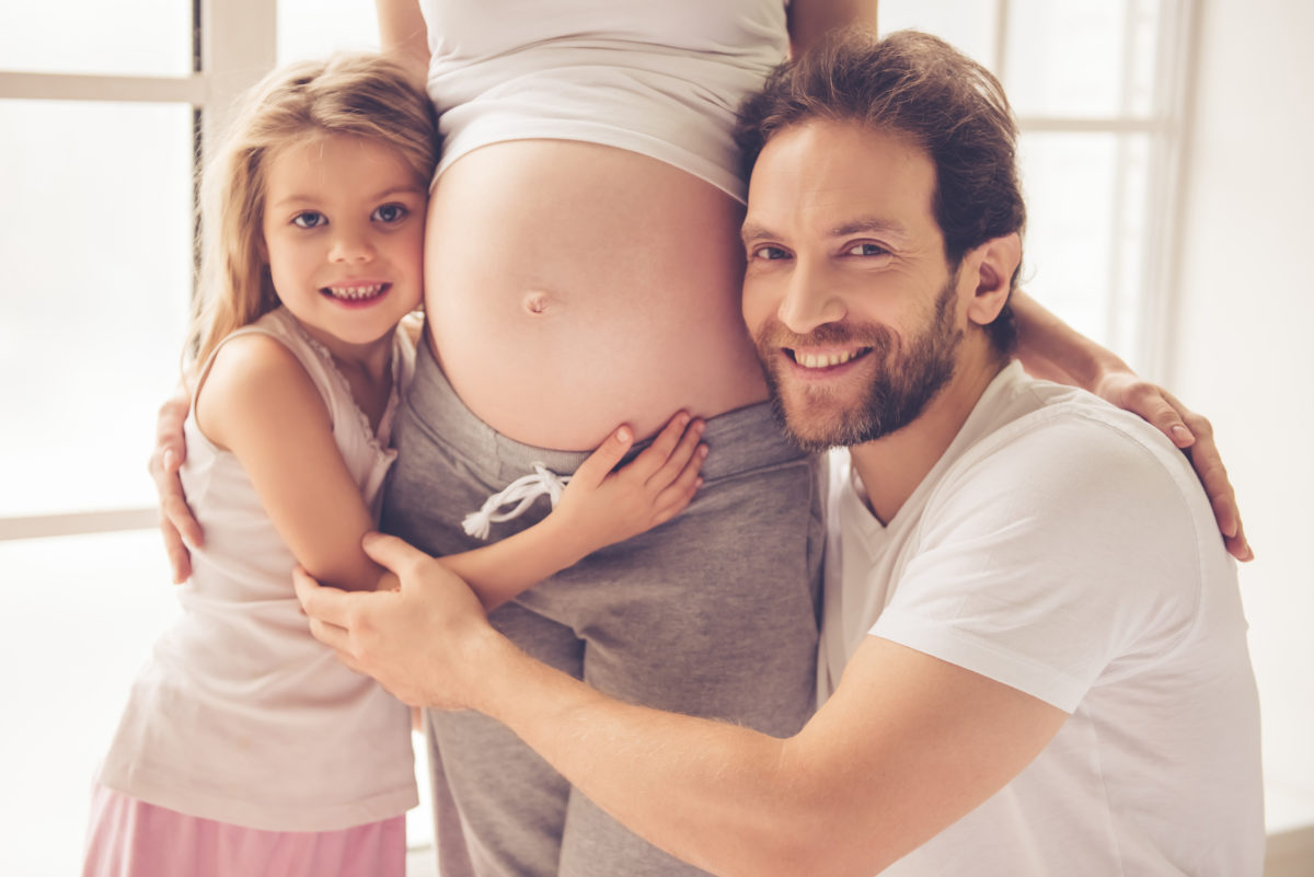 Vater und große Schwester an Babybauch