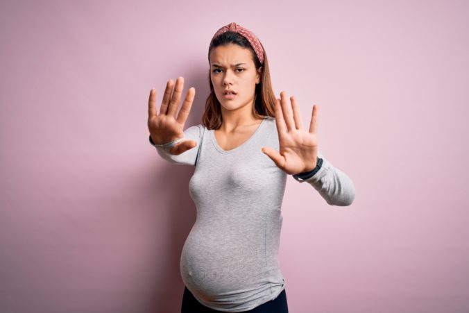 Wütende Schwangere hält Hände hoch