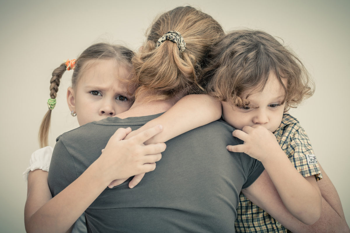 Traurige Kinder umarmen ihre Mutter