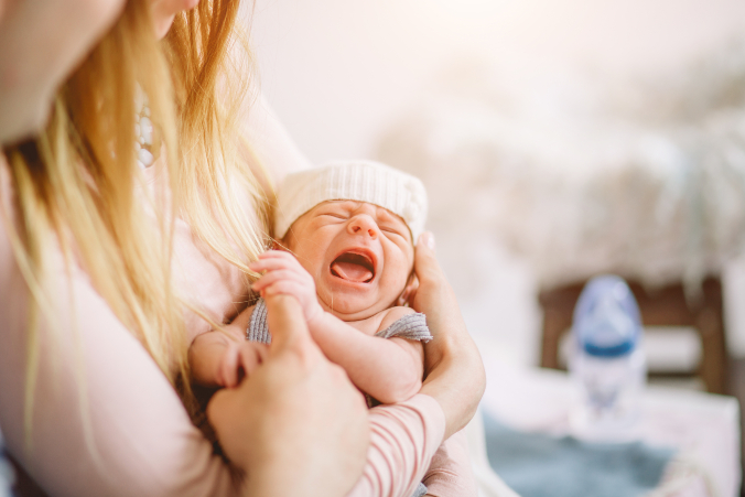 Baby schreit auf dem Arm der Mama