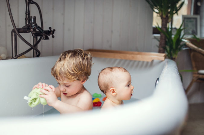 Kleinkind und Baby spielen in der Badewanne