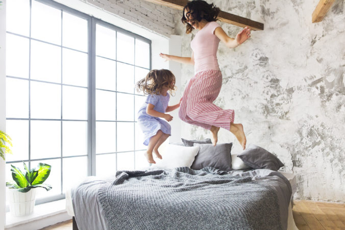 Mama und Kind hüpfen auf dem BEtt