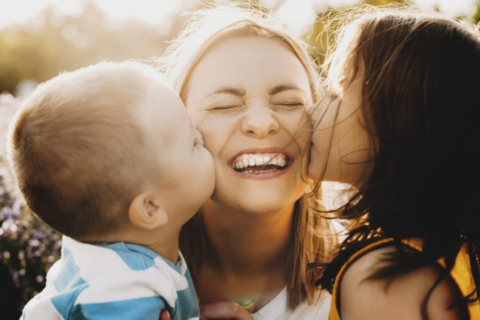 Kinder küssen Mama auf Wange