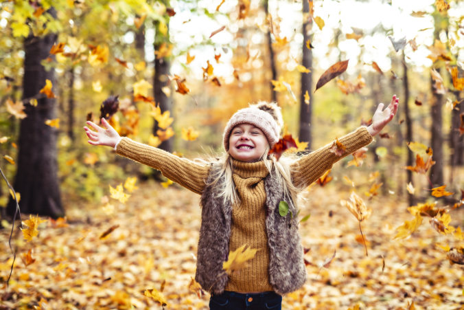 Kind schmeißt herbstblätter in die Luft