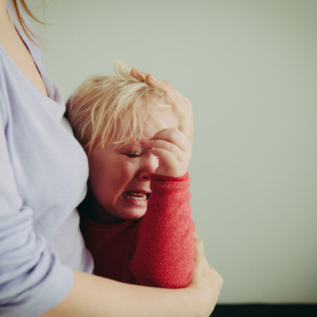 Kind weint im Arm von Mama