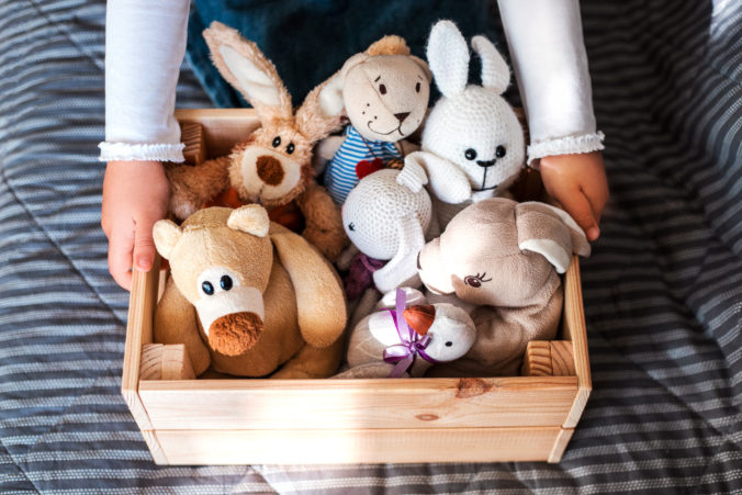 KInderhände greifen an Kiste voll mit Kuscheltieren