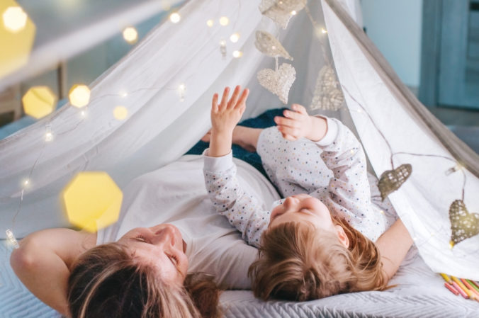 Mutter und kleine Tochter liegen unter Tipi