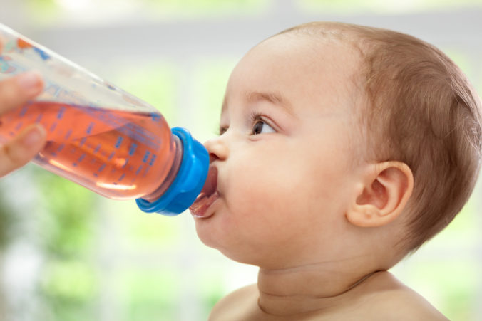 Baby trinkt Tee aus einer Flasche