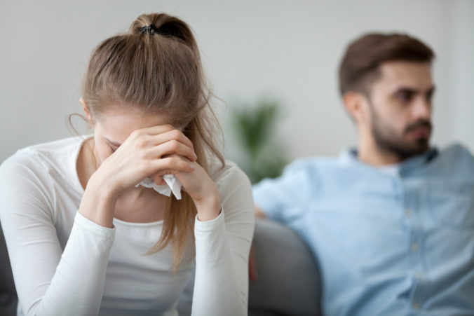 Getrenntes Paar Mann im Hintergrund Frau hat die Hände vor dem Gesicht