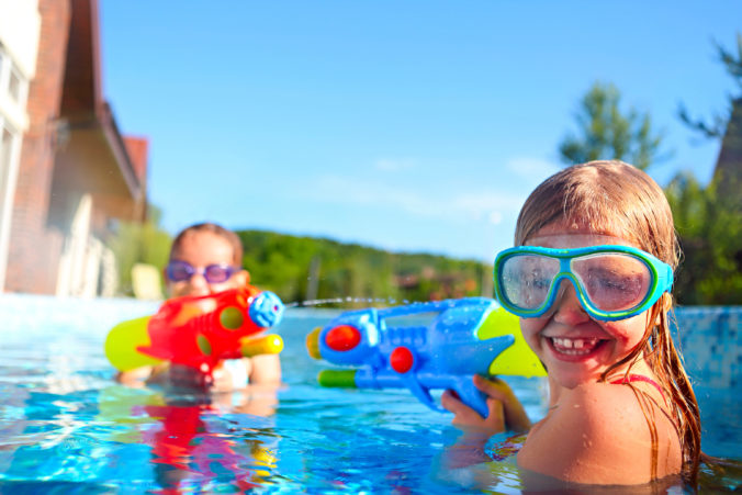 Zwei Mädchen spielen im Pool mit Wasserpistolen